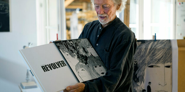 Der Grafiker Klaus Voormann hält das von ihm gestaltete Cover Revolver der Beatles in den Händen