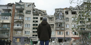 Menschen betrachten ein beschädigtes Gebäude nach einem Raketenangriff in Slowjansk