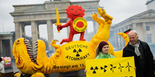 ürgen Trittin (Bündnis 90/Die Grünen), Mitglied des Deutschen Bundestages und ehemaliger Umweltminister, steht neben einer Aktivistin vor einer Dinosaurier-Figur und der roten Sonne, teil des Anti-Atomkraft-Logos, bei einer Aktion der Umweltorganisation Greenpeace vor dem Brandenburger Tor. Die Aktion soll die Abschaltung der letzten drei deutschen Kernkraftwerke feiern.