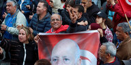 Ein Mann hält ein Plakat mit dem Konterfei des tunesischen Präsidenten, er steht in einer menschenmenge