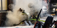 Einsatzkräfte der Feuerwehr löschen von der Straße aus knied den Brand in einem Keller