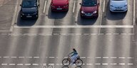 Eine Radfahrerin vor parkenden Autos