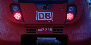 Ein Zug der Deutschen Bahn DB mit roten Lichtern steht am frühen Morgen im Hauptbahnhof Rostock