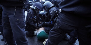 Polizisten drücken einen Demonstranten zu Boden.
