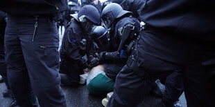 Polizisten drücken einen Demonstranten zu Boden.