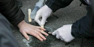 Eine festgeklebte Hand wird vom Asphalt gelöst