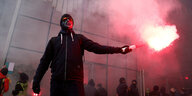 Eine maskierter Demonstrant hät Pyrotechnik in den Händen