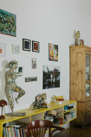 An der Wand hängen Bilder und Fotos, Skulpturen stehen auf einem Sideboard