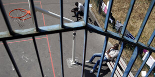 Zwei Jugendliche sitzen neben einem Basketballfeld