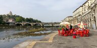 Rote Stühle eines Gastronomiebetriebes am Flussufer des Po, der fast ausgetrocknet ist