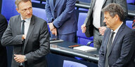 Christian Lindner und Robert Habeck stehen hinter ihren Regierungsbänken im Bundestag und schauen sich kritisch an