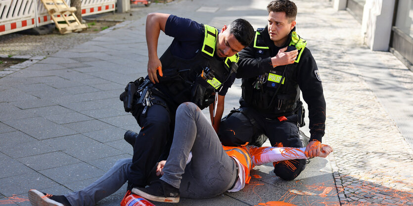 Zwei Polizisten bezwingen einen Klimaaktivisten