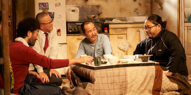 Vier Männer sitzen an einem Küchentisch
