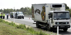 Lastwagen, in dem die Leichen von Flüchtlingen gefunden wurden, auf dem Seitestreifen der Autobahn - dahinter Einsatzfahrzeuge.