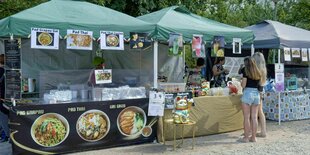 Zwei Personen stehen vor einem Stand mit Thai-Essen