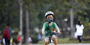 Ein Kind mit Mundschutzmaske auf seinem Fahrrad