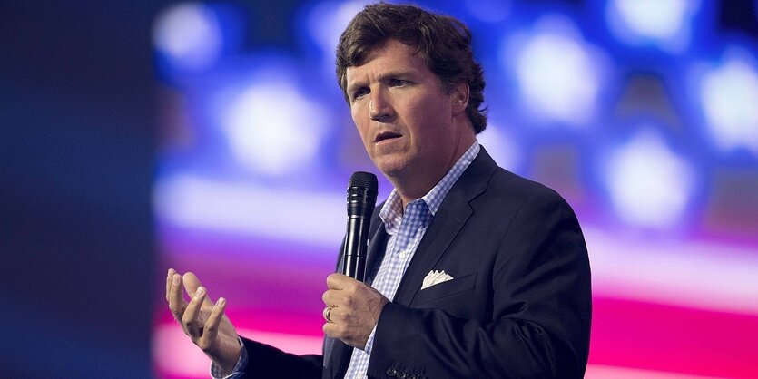 Tucker Carlson steht an einem Rednerpult