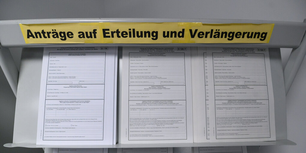 "Anträge auf Erteilung und Verlängerung" steht auf einem Regal mit Anträgen für Aufenthaltstitel.