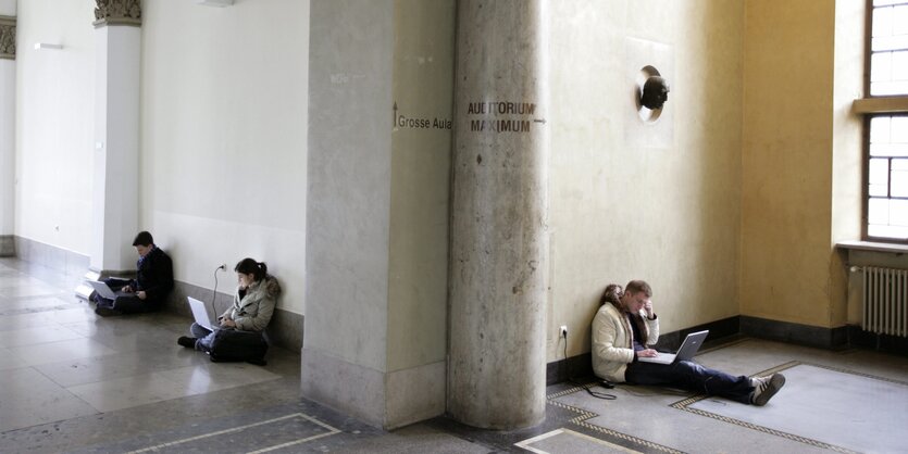 Studierende sitzen auf dem Boden vor ihren Laptops rum