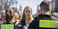 Eine junge Frau steht einem Polizisten und einer Polizistin gegenüber
