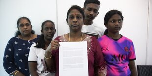 Eine Gruppe von fünf menschen, die Frau im Vordergrund hält ein Blatt Papier in den Händen