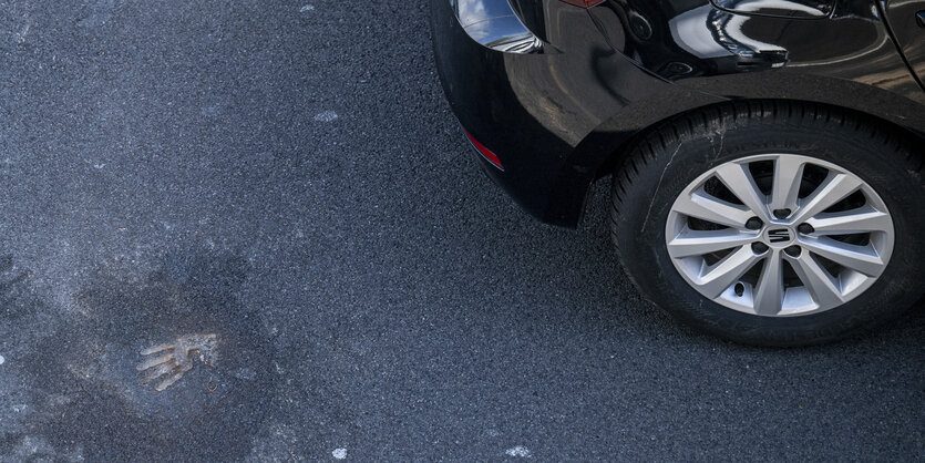 Handabdruck auf der Straße neben einem Auto