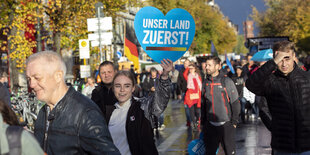 blaues Herz mit Aufschrift "Unser Land zuerst" wird von einer jungen Frau mit Zahnspange bei einer AFD Demo gehalten