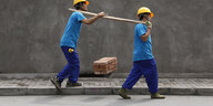 Zwei Bauarbeiter tragen Bausteine