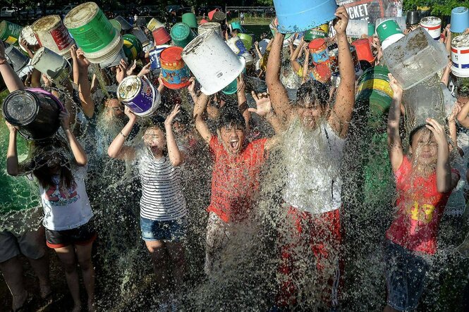 Kinder schütten sich Eimer mit Wasser über den Kopf