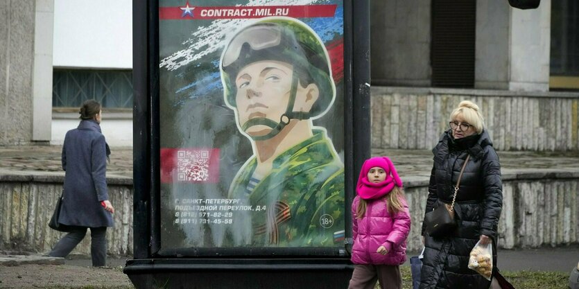 Passantinnen gehen an einem Plakat vorbei, auf dem die Illustration eines uniformierten Soldaten zu sehen ist