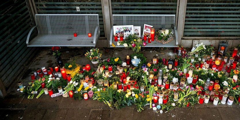 Blumen und Kerzen neben Sitzbänken an einem Bahnhof