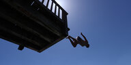 Ein Mann springt von einem hölzernen Sprungturm