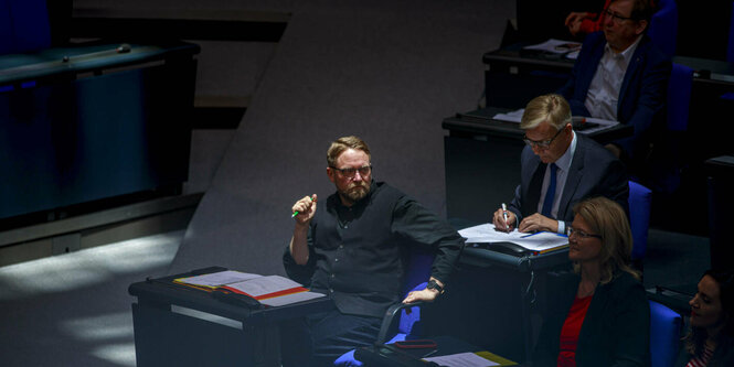 Jan Korte sitzt im Sonnenlicht im Bundestag