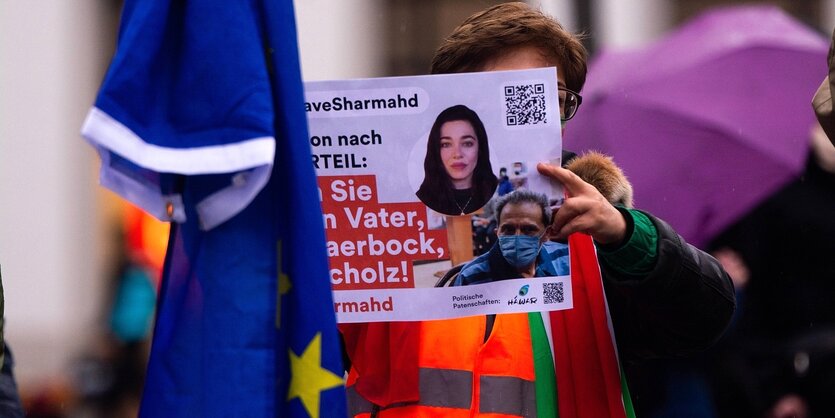 Eine Frau hält ein Protestplakat und die Fahne der EU