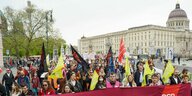 Demonstrationszug in Berlin mit Transparent "Arbeiter_innen Kampftag 1. Mai, im Hintergrund das Berliner Stadtschloss