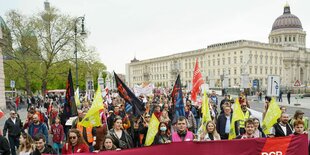 Demonstrationszug in Berlin mit Transparent "Arbeiter_innen Kampftag 1. Mai, im Hintergrund das Berliner Stadtschloss