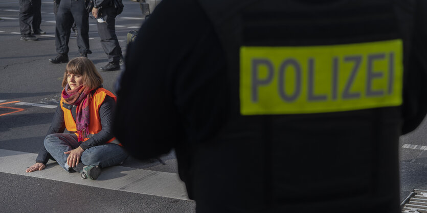 Ein Polizist von hinten, guckt in Richtung einer Blockiererin