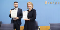 Marco Buschmannn und Lisa Paus stehen gemeinsam auf der Bundespressekonferenz und halten das Papier zum Selbstbestimmungsgesetz in die Kamera
