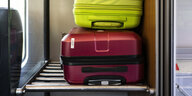 Zwei Koffer liegen übereinandergestapelt in der Gepäckablage eines Zuges