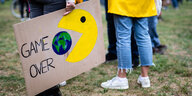 Bei einer Fridays for Future-Demonstration hält jemand ein Schild auf dem ein Kopf aus dem Videospiel Pac-Man einen Erdball verschlingt, daneben steht "Game over".