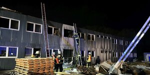 Feuerwehrleute löschen den Brand in einer für die Unterbringung von Geflüchteten vorgesehenen Containeranlage im hessischen Roßdorf