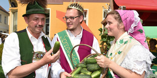 Drei Menschen in Trachten mit Gurken