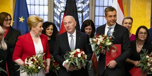 Mehrere Menschen schauen in die Kamera und halten dabei einen Blumenstrauß in der Hand