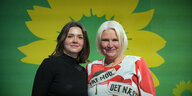 Zwei Frauen stehen vor einem Logo der Grünen
