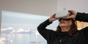 Eine Frau schaut in einer Ausstellung in eine Virtual-Reality-Brille