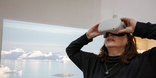 Eine Frau schaut in einer Ausstellung in eine Virtual-Reality-Brille