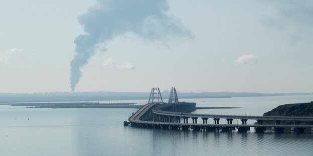 Rauch über einer Stadt, im Vordergrund eine Brücke
