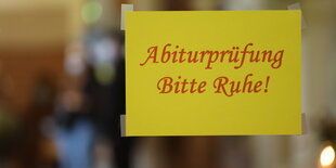 Ein Schild mit der Aufschrift "Abiturprüfung - Bitte Ruhe!" hängt im Flur einer Schule.