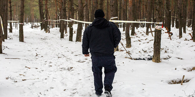 Rückenansicht einer Person auf einem Schnee bedeckten Waldboden