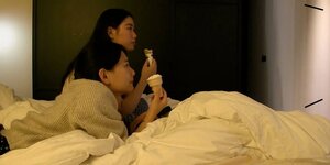 Zwei Mädchen, Eis essend auf einem Bett